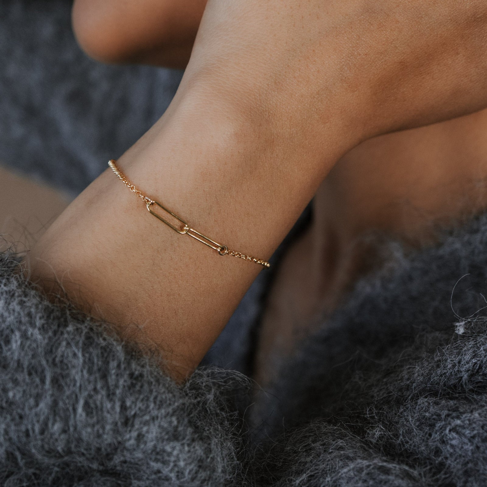 Close-up of a person wearing a gold bracelet with a blurred background