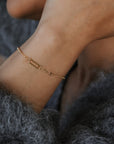 Close-up of a person wearing a gold bracelet with a blurred background