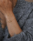 Person wearing a gold bracelet on a gray sweater