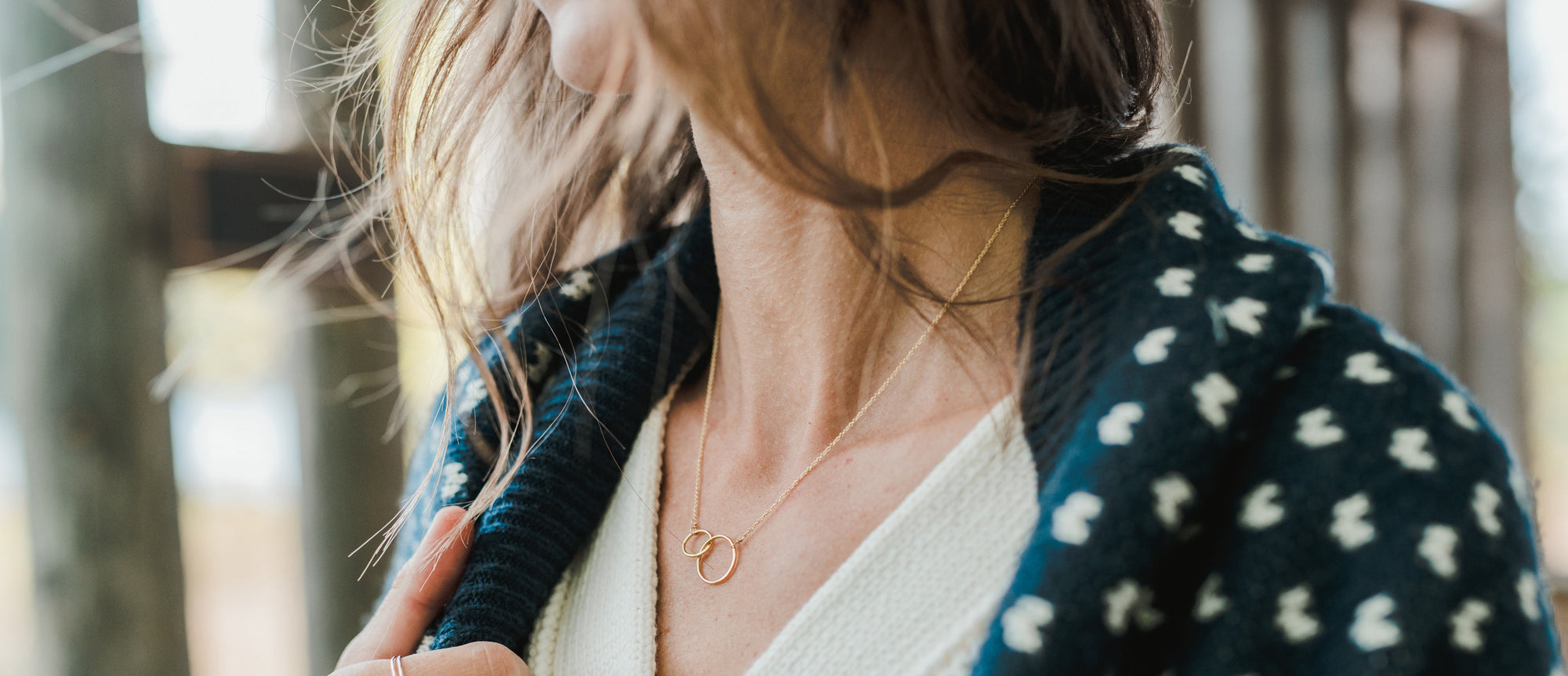 Featured image at the top of Becoming Jewelry's website featuring a woman wearing a necklace and blanket around her shoulders.