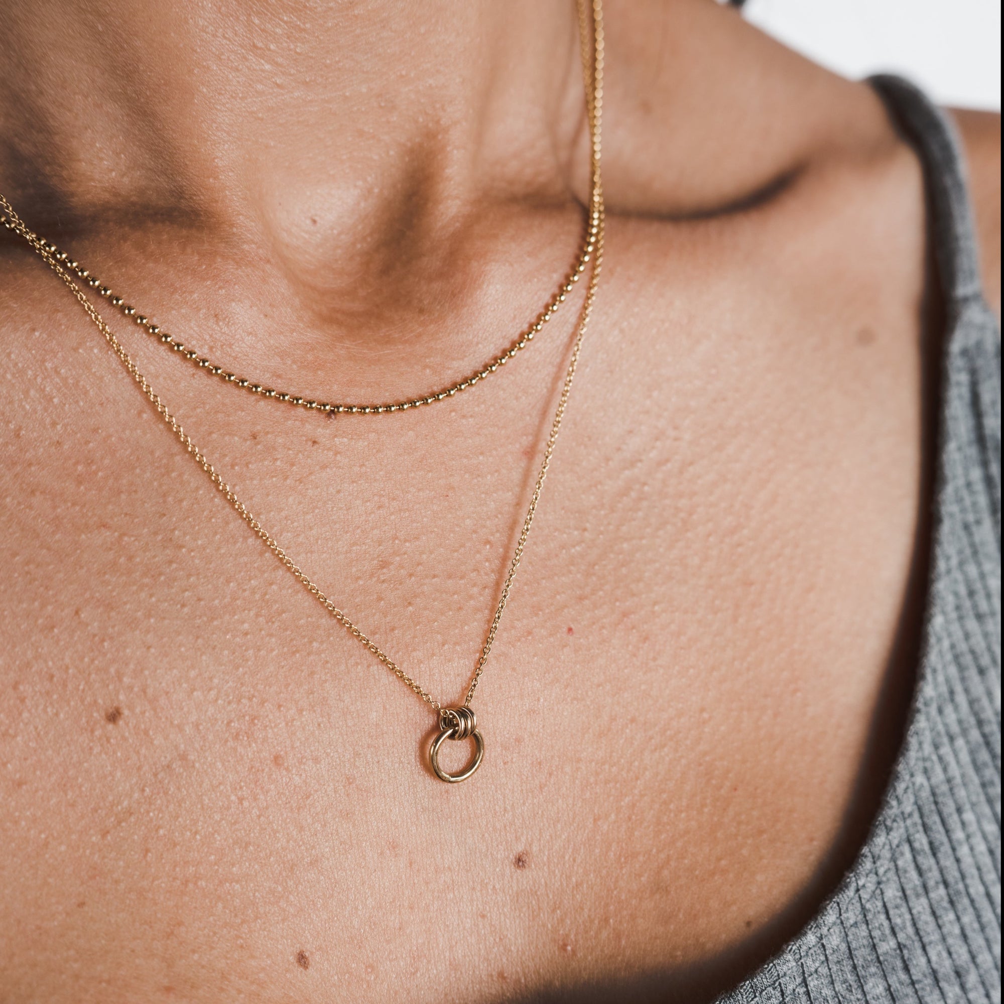 A close-up of a person wearing a Becoming Jewelry Family Circle Necklace with a circle charm pendant.