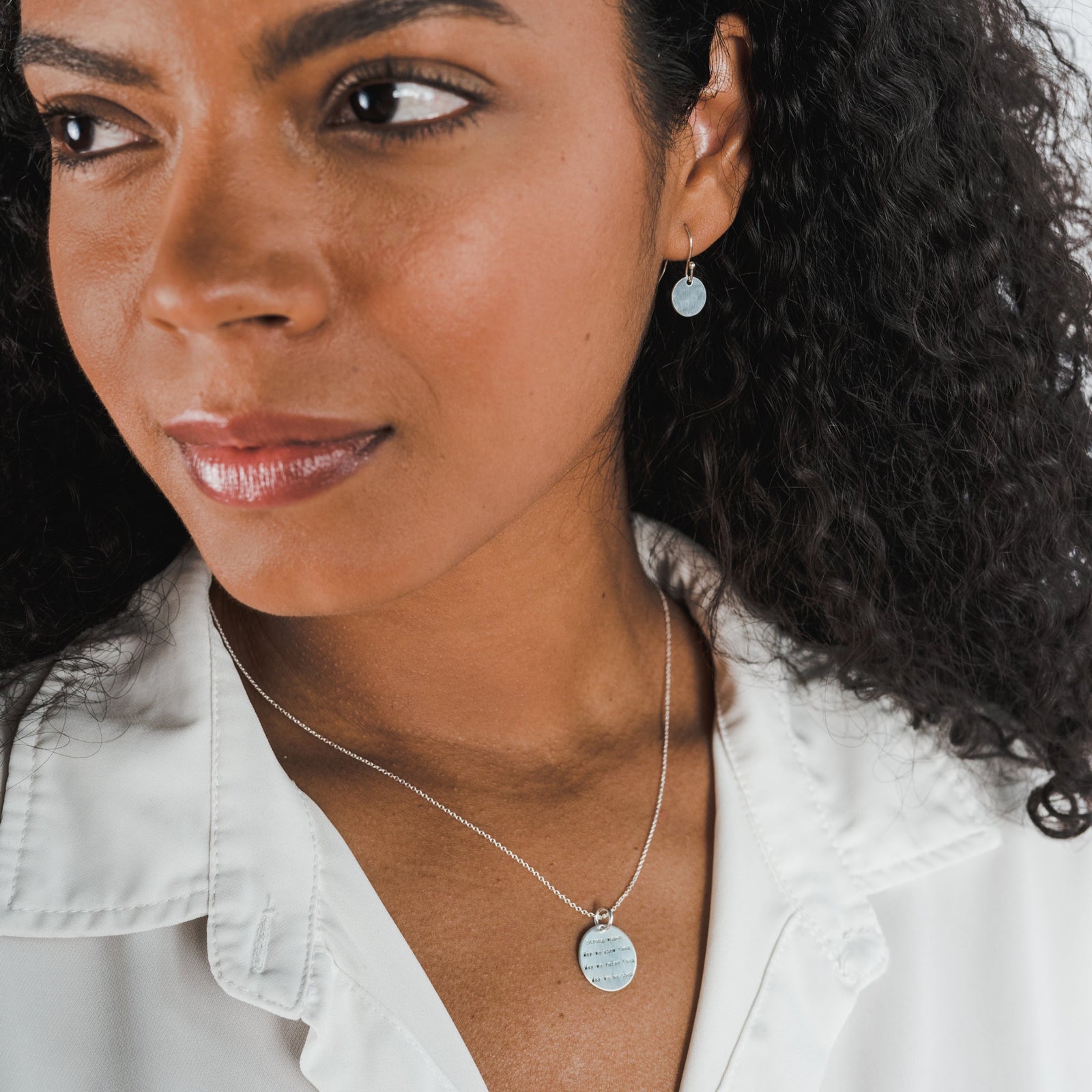 A woman wearing a Becoming Jewelry Strong Women Necklace and earrings.