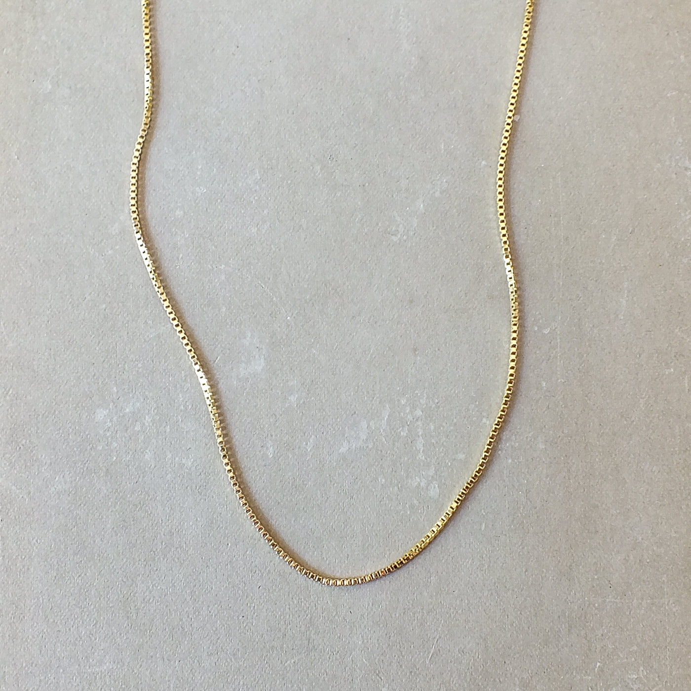 Becoming Jewelry&#39;s Gold filled box chain necklace on a plain background.