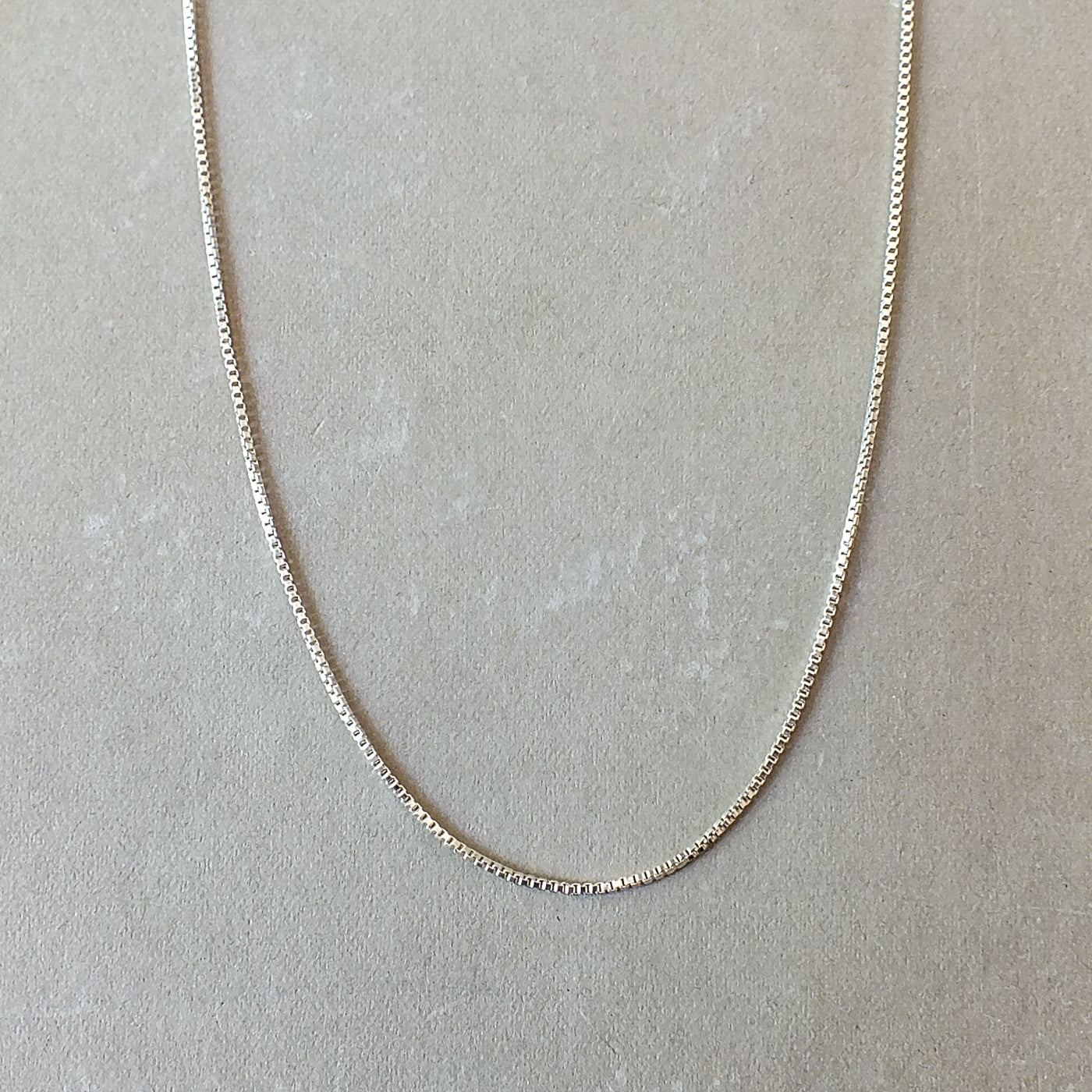 Becoming Jewelry Sterling silver box chain necklace on a grey background.