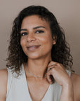 Woman wearing a starburst chain necklace and a beige sleeveless top against a plain background