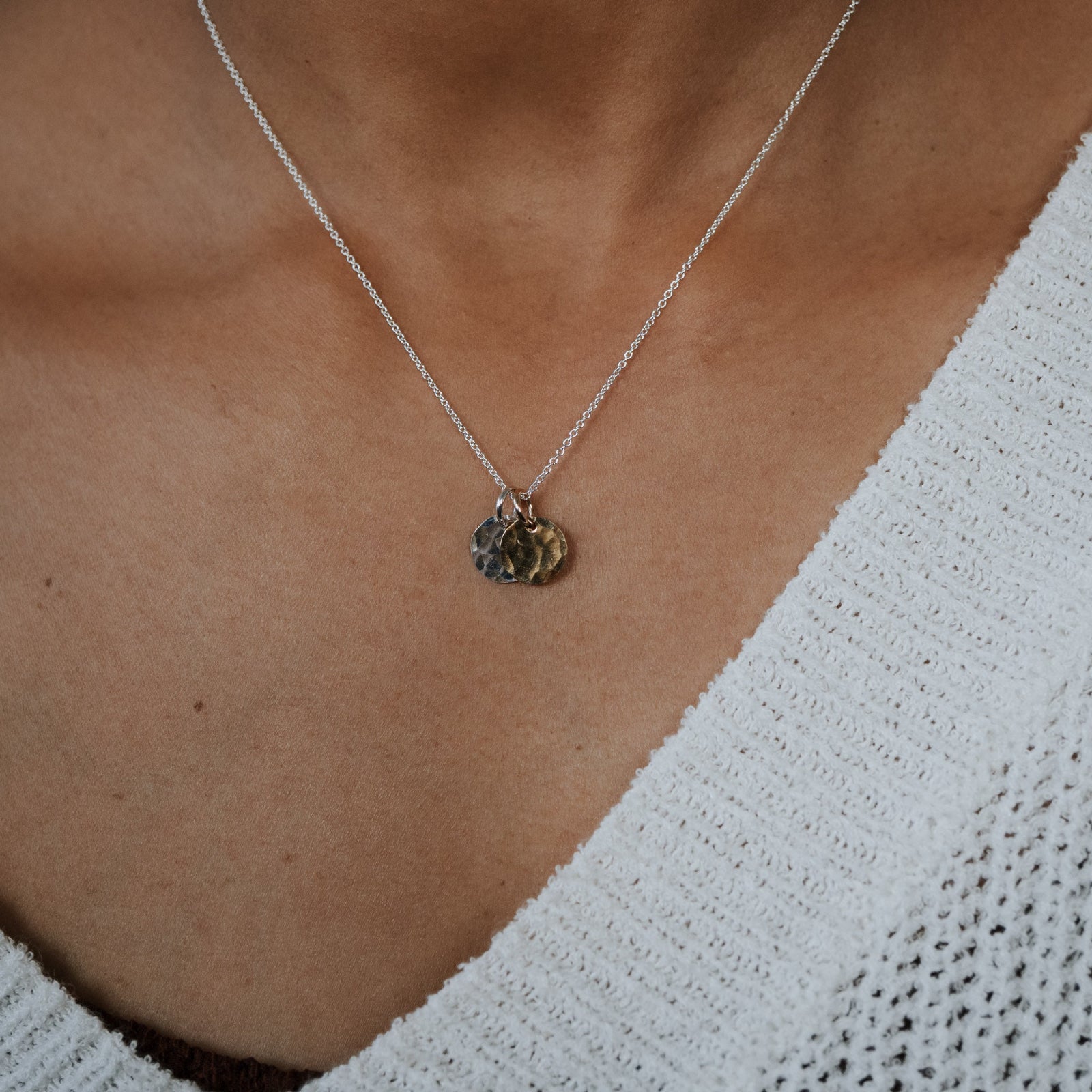 Necklace with heart-shaped pendants worn by a person in a white textured garment.