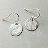 A pair of Becoming Jewelry Hammered Disc Drop Earrings, small displayed on a gray background.