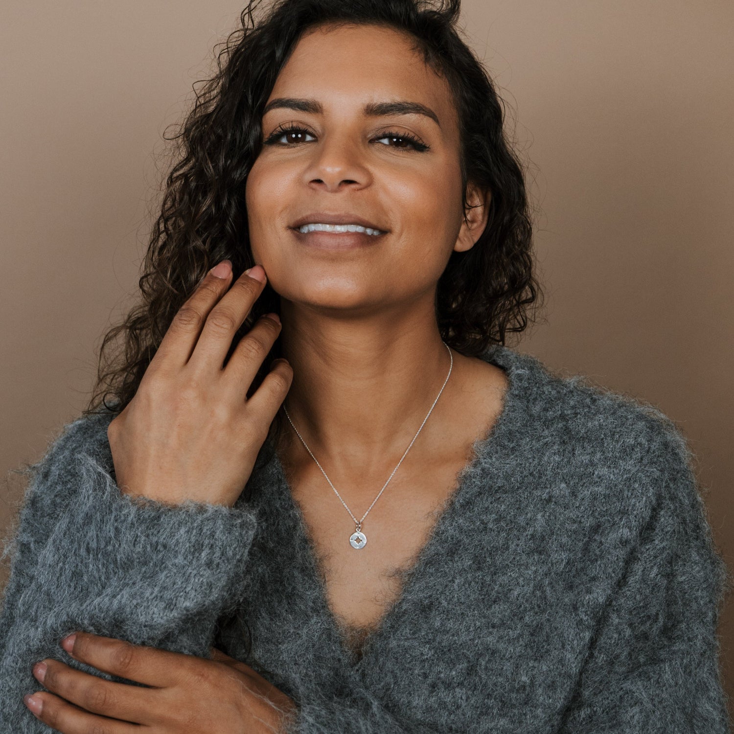 Woman wearing a gray sweater against a beige background
