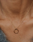Gold necklace with a circular pendant on a person's neck