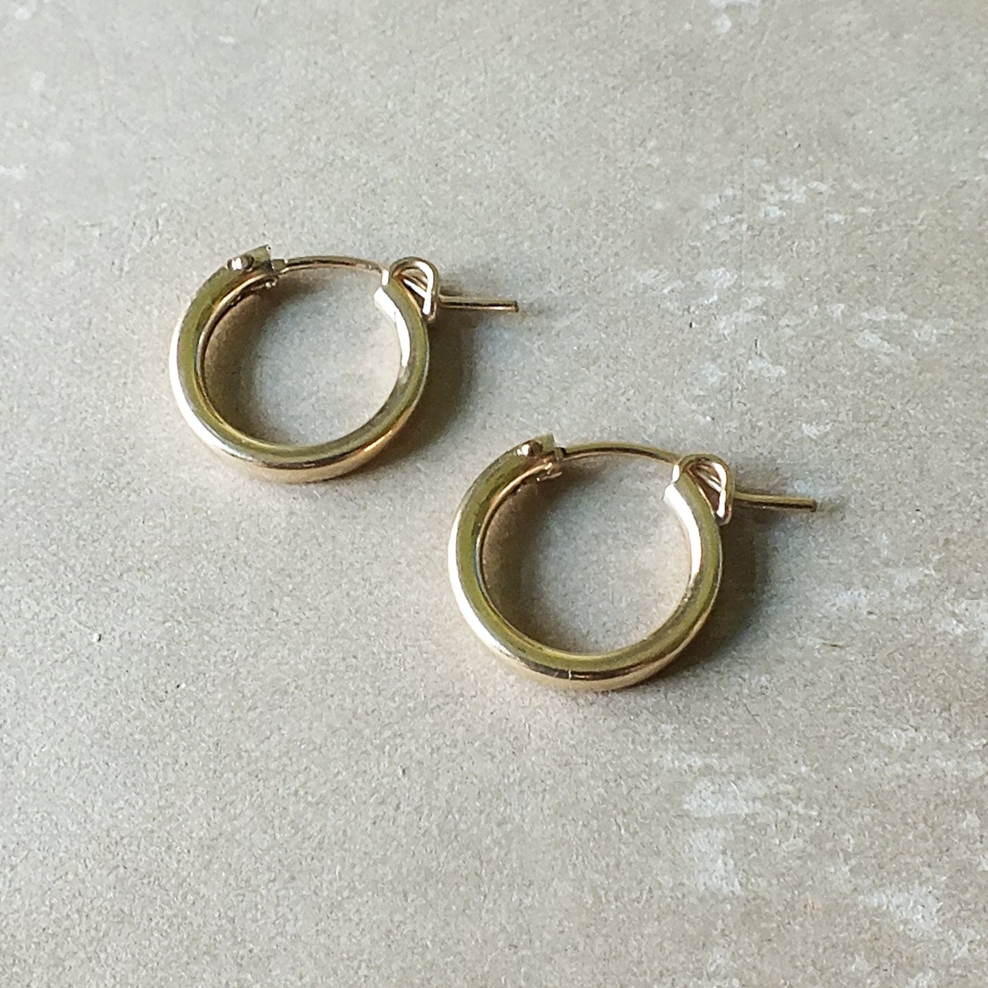 A pair of Becoming Jewelry Everyday Hoop Earrings, medium on a gray surface.