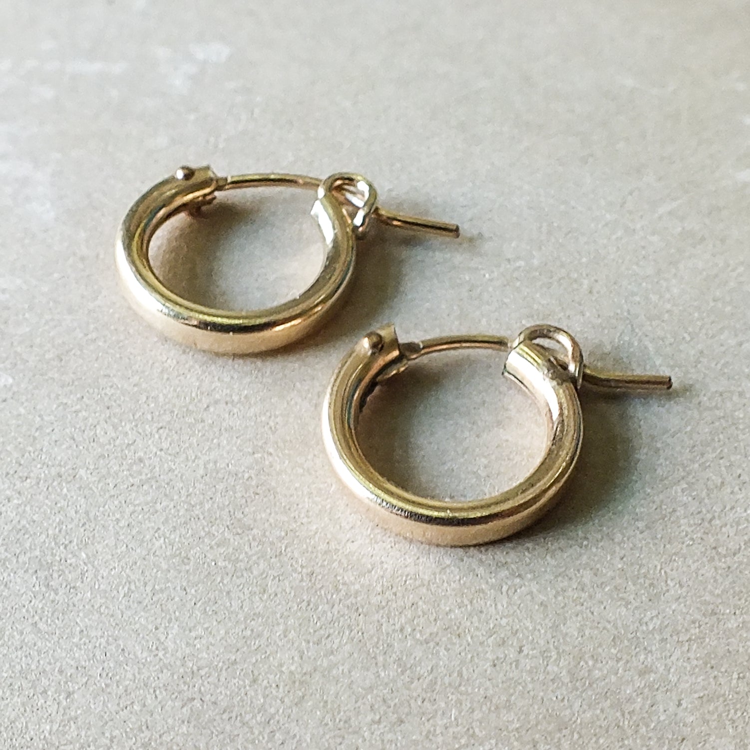 A pair of Becoming Jewelry Everyday Hoop Earrings, small on a light surface.