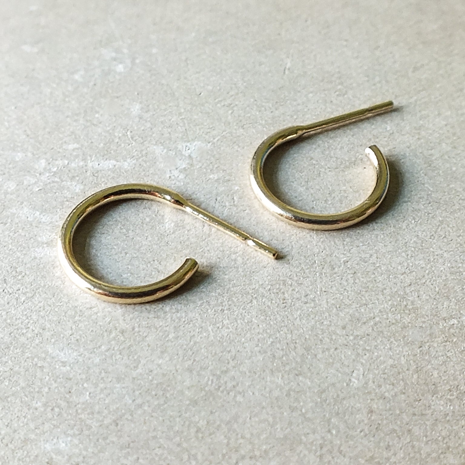 Pair of Becoming Jewelry Open Hoop Earrings, small on a light surface.