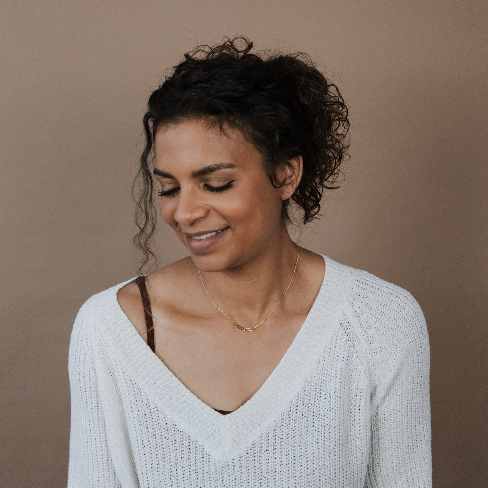 Woman wearing a white sweater against a brown background