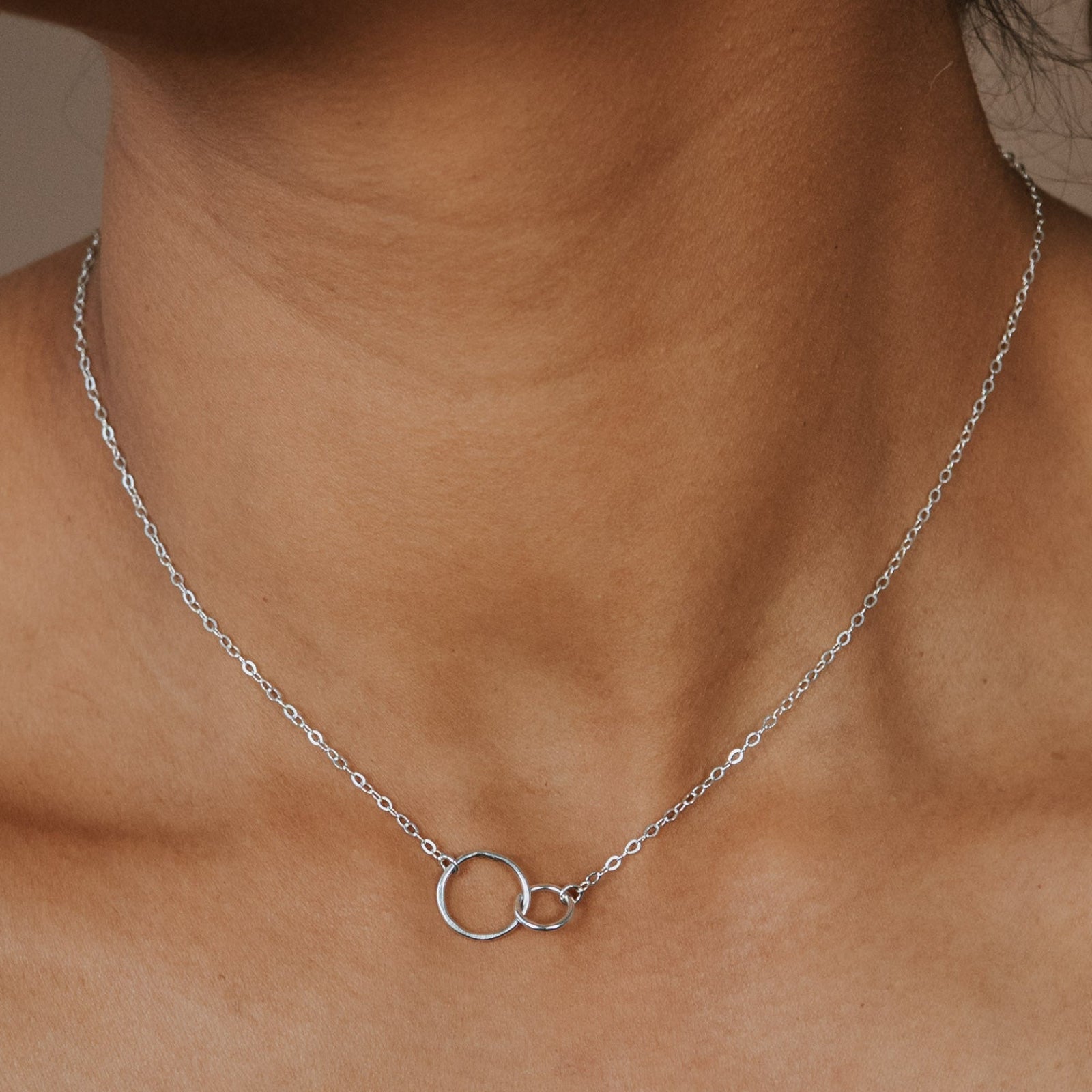 Necklace with a small pendant worn by a person against a neutral background