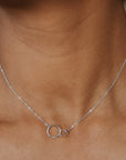 Necklace with a small pendant worn by a person against a neutral background