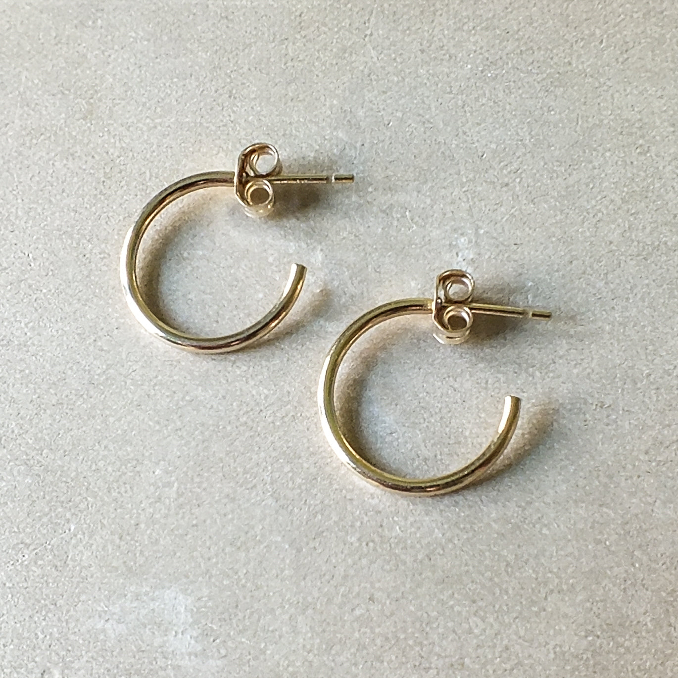 A pair of gold filled, medium-sized Open Hoop Earrings by Becoming Jewelry on a light background.