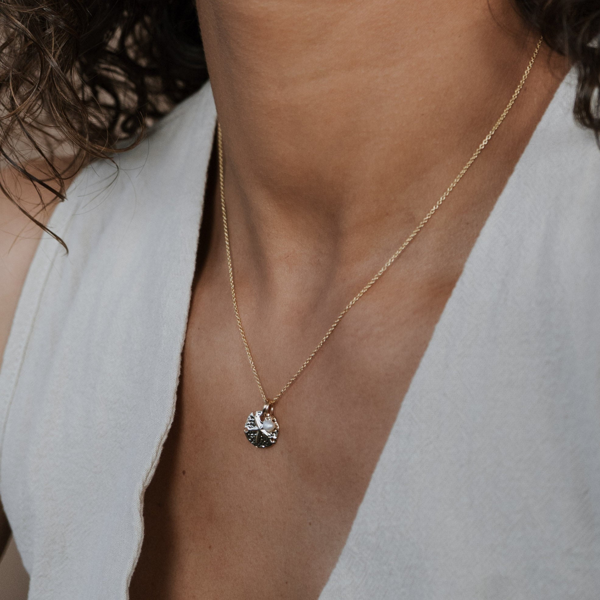 Necklace with a pendant worn by a person in a light-colored outfit