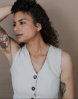 Woman with tattoos and a sleeveless top against a plain background
