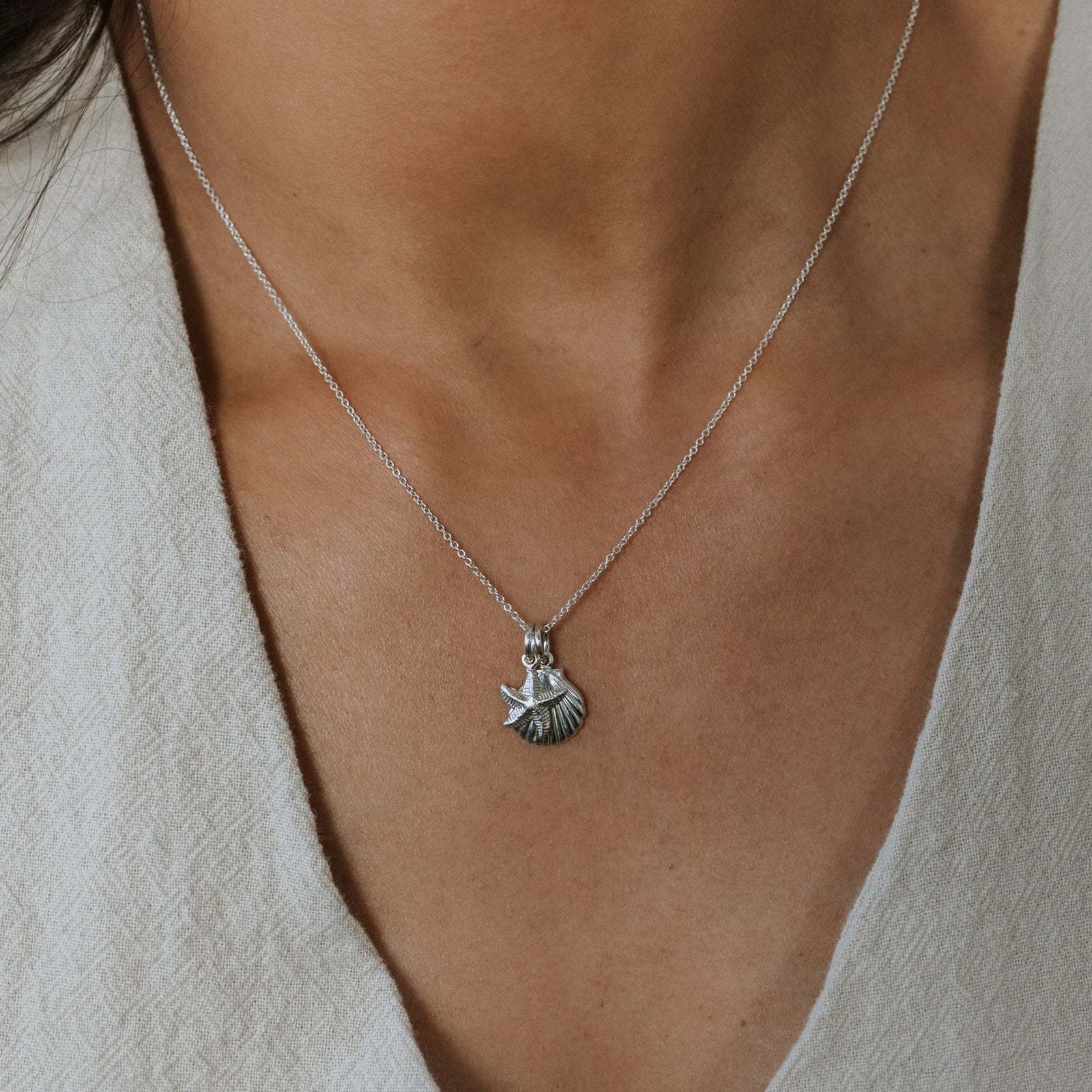 Necklace with a pendant worn by a person in a light-colored outfit