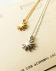 Two sun-shaped necklaces on a vintage postcard