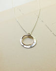 Silver necklace with a circular pendant on a beige card