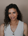 Woman wearing a light gray sleeveless top with buttons against a plain background