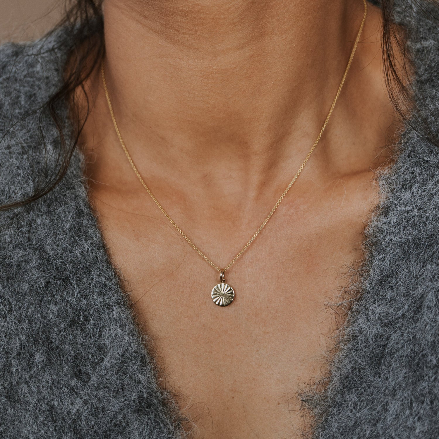 Necklace with a small pendant worn by a person against a neutral background