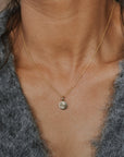 Necklace with a small pendant worn by a person against a neutral background