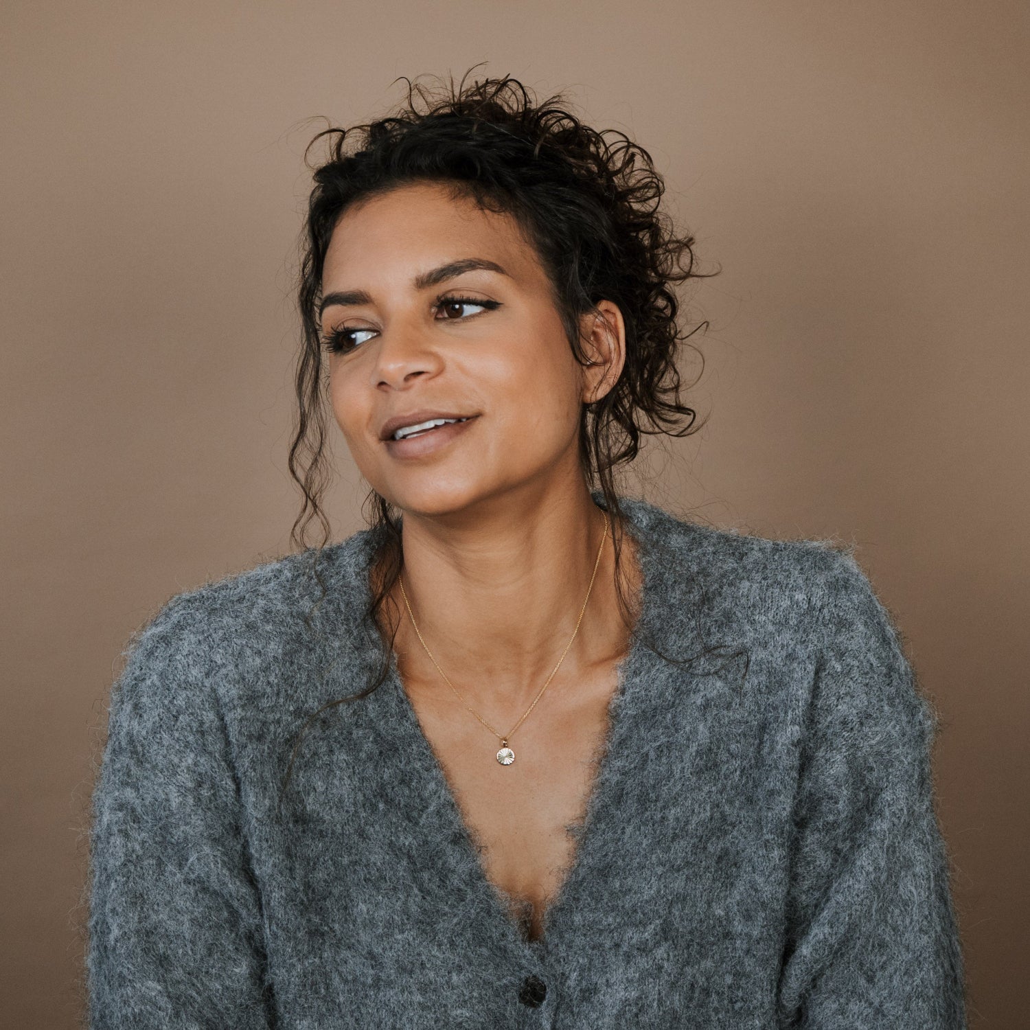 Woman wearing a gray cardigan against a brown background