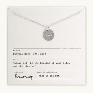Becoming Jewelry's Badass Necklace features a gold filled charm with "badass" inscription on a card featuring a quote by Nora Ephron.