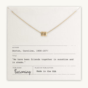 A Friends Beads Necklace from Becoming Jewelry with a lock pendant displayed on a card with a friendship quote by Caroline Norton.