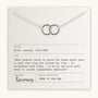 A Joined for Life necklace with intertwined circles lies on a card quoting George Eliot (1819-1880) about human connection. The card indicates the quote is from Becoming Jewelry and notes it was made in the USA.