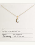 Gold-filled Love You To The Moon Necklace charm pendant on a chain displayed on a card with the inscription "love you to the moon and back" by Becoming Jewelry, made in the USA.