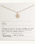 Climb That Mountain Necklace displayed on a card with an inspirational quote about climbing mountains and living memorable moments, labeled as "Becoming Jewelry" and "made in the USA". This Mountain Charm piece is Gold Filled.