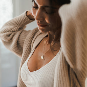 Woman wearing a Blossom Necklace by Becoming Jewelry and a beige cardigan.