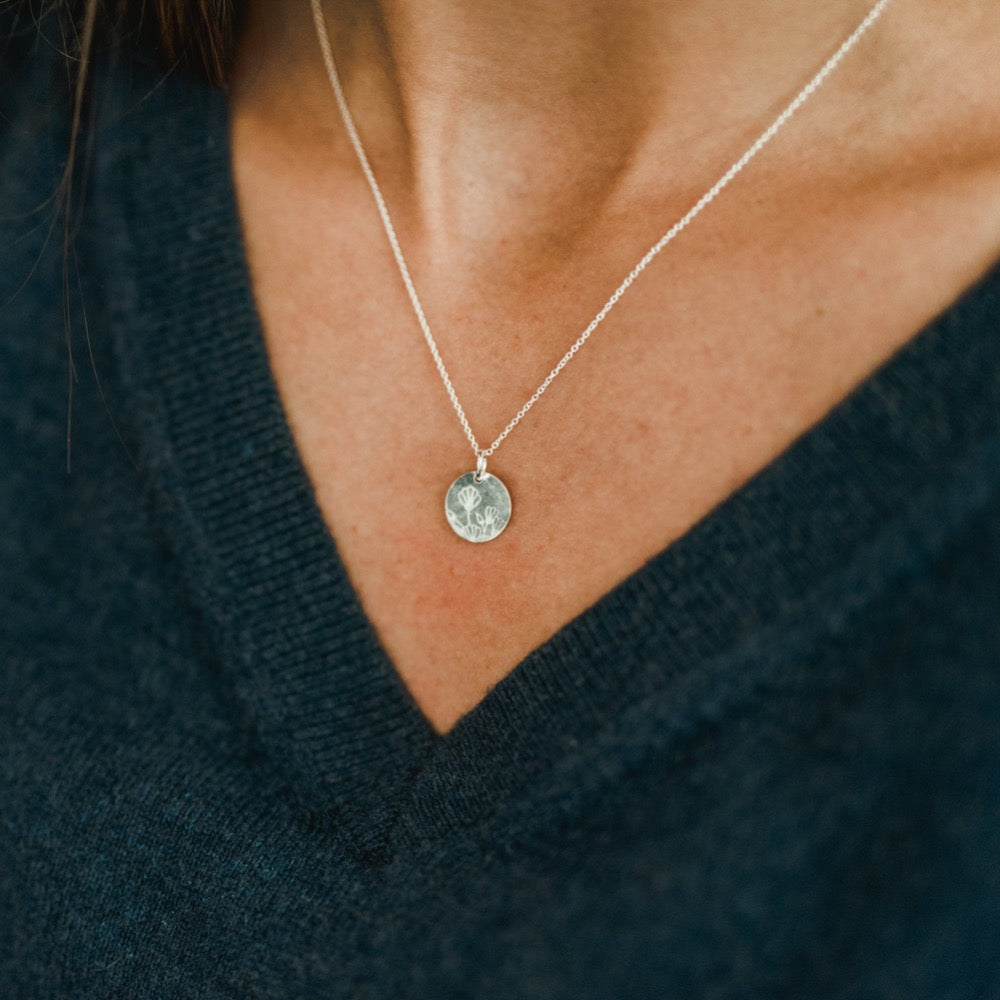 Woman wearing a Becoming Jewelry Blossom Necklace with a v-neck sweater.