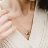 A person adjusting a delicate Becoming Jewelry Loved Necklace with a small pendant.
