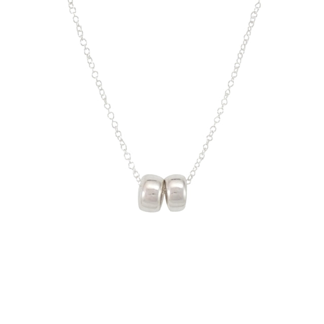 The Friends Beads Necklace by Becoming Jewelry is a delicate silver chain featuring two small silver beads side by side in the center, making it a meaningful gift perfect for dearest friends.