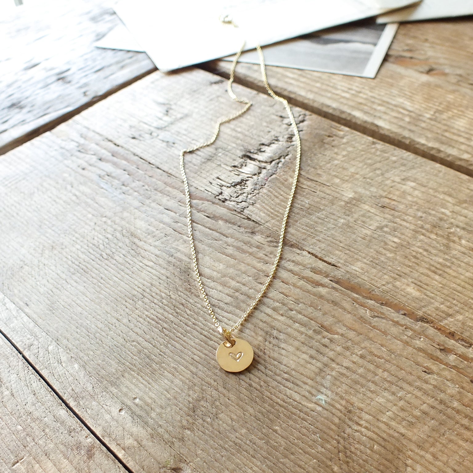 Becoming Jewelry's Heart Necklace displayed on a wooden surface.