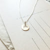 Over the Rainbow Necklace by Becoming Jewelry, featuring a stamped design, resting on a sheet of paper with printed text.