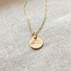 You Are My Sunshine Necklace" by Becoming Jewelry, featuring a sunshine charm, lying on a textured fabric surface.
