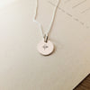 Round pendant Light Within Necklace with a starlight charm engraving on a light background by Becoming Jewelry.