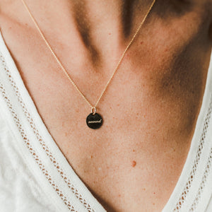 Onward Necklace by Becoming Jewelry with a circular pendant worn by a person with a visible décolletage.