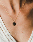 Onward Necklace by Becoming Jewelry with a circular pendant worn by a person with a visible décolletage.