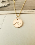 Wave Round Charm Necklace by Becoming Jewelry displayed on a book page.