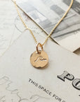 Becoming Jewelry's Swim the Sea Necklace with a wave charm design displayed on a piece of paper.