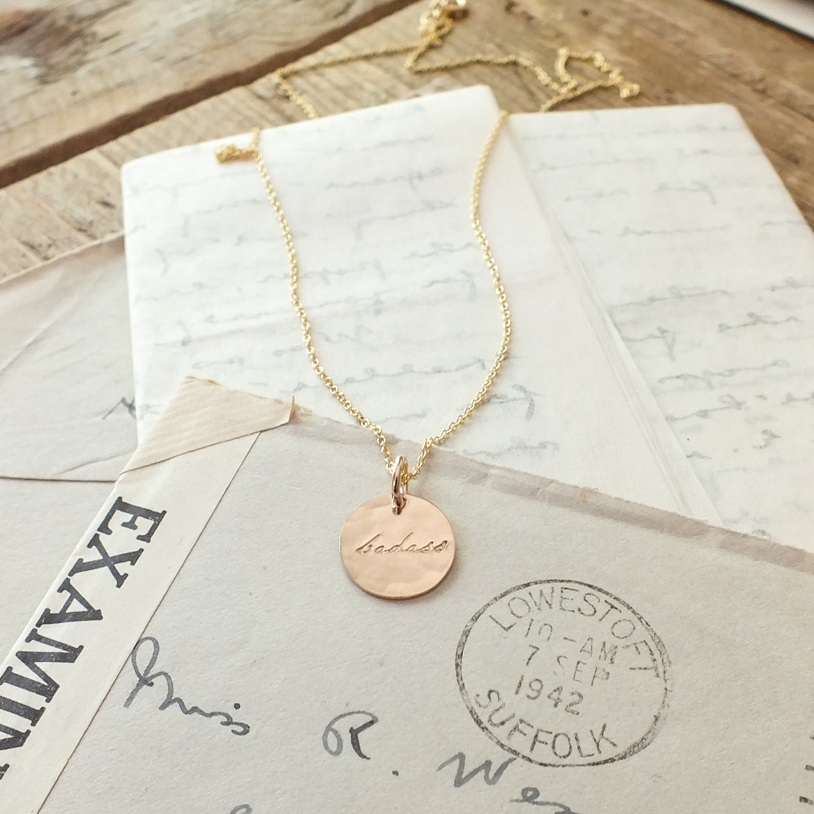 Badass Necklace by Becoming Jewelry displayed on vintage handwritten letters.
