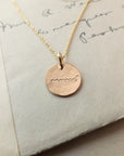A Becoming Jewelry Onward Necklace with the word "onward" engraved on it, displayed on a piece of paper with cursive handwriting.